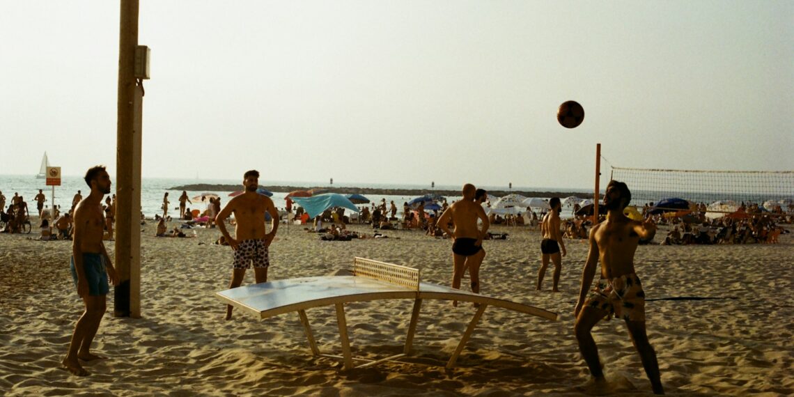 a group of people playing volleyball on a beach