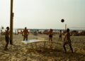 a group of people playing volleyball on a beach