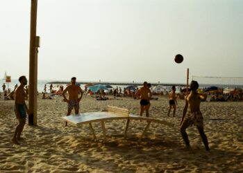 a group of people playing volleyball on a beach