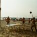 a group of people playing volleyball on a beach